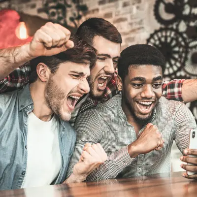 trois fans célébrant devant un téléphone